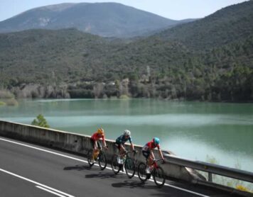 Три гонщика в отрыве проезжают мимо одного из многочисленных озер на 169,2-километровом этапе из Сорта в Ллейду Вуэльта Каталонии 2024