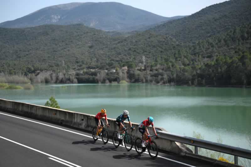 Три гонщика в отрыве проезжают мимо одного из многочисленных озер на 169,2-километровом этапе из Сорта в Ллейду Вуэльта Каталонии 2024