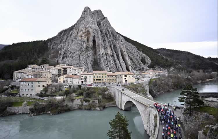 Пелотон проезжает мимо скалы Роше де ла Баум в Систероне на шестом этапе Париж-Ницца 2024