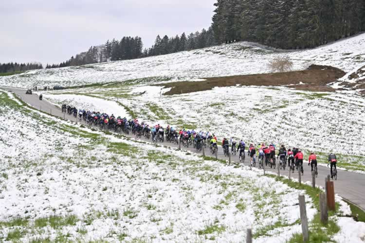 Пелотон едет по заснеженному ландшафту на 165,7-километровом этапе 1 из Шато-д'Оэкса во Фрибург